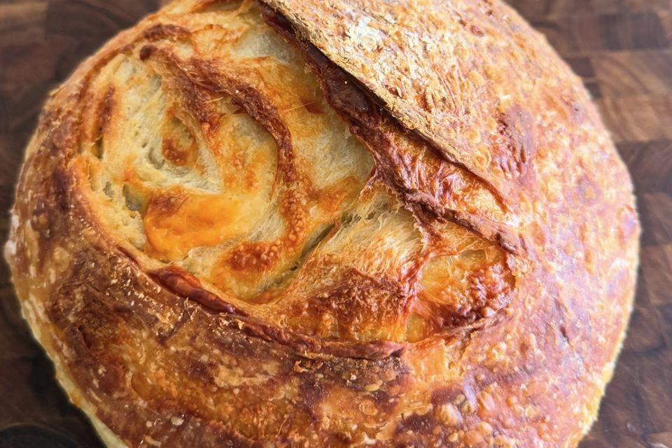 A cheddar sourdough boule on a walnut board