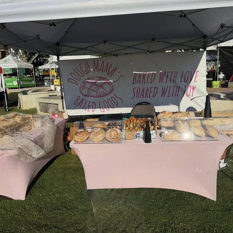 Dough Mama's market table with a pink banner and fresh loaves