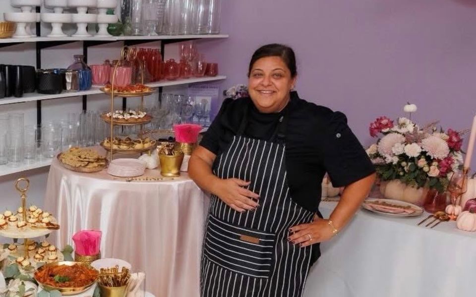 Chef Taisha in her apron at a Dough Mama’s event in Florida, beside tables of tiered desserts and small bites